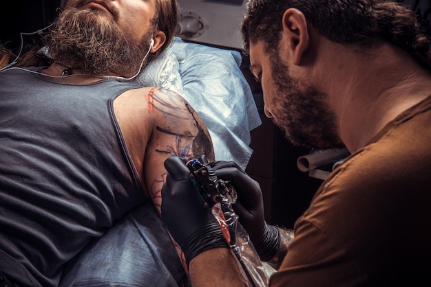 Profesjonalny Tatuator Pokazujący Proces Wykonywania Tatuażu W Salonie Tatuażu./profesjonalny Tatuator Wykonuje Fajny Tatuaż W Studio Tatuażu.