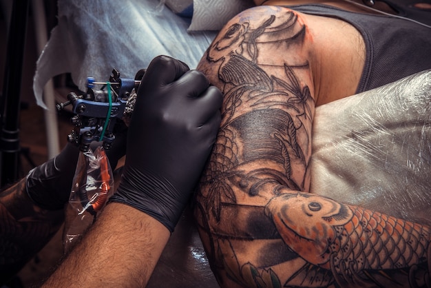 Profesjonalny tatuator pracuje w salonie tatuażu