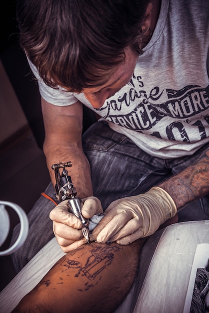 Profesjonalny tatuator wykonuje fajny tatuaż w salonie tatuażu