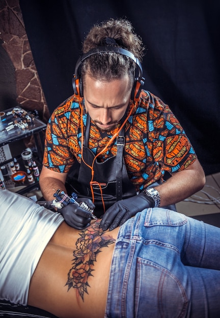 Profesjonalny tatuator wykonuje tatuaż na skórze swojego klienta