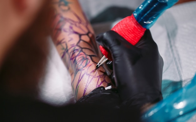 Profesjonalny tatuażysta wykonuje tatuaż na dłoni młodej dziewczyny.