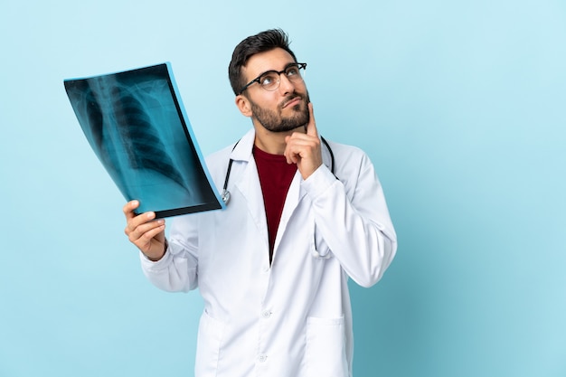 Profesjonalny traumatolog posiadający radiografię na białym tle na niebieski myślący pomysł