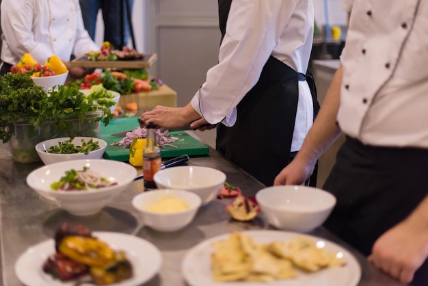 Profesjonalny zespół kucharzy i szefów kuchni przygotowujących posiłek w ruchliwej hotelowej lub restauracyjnej kuchni