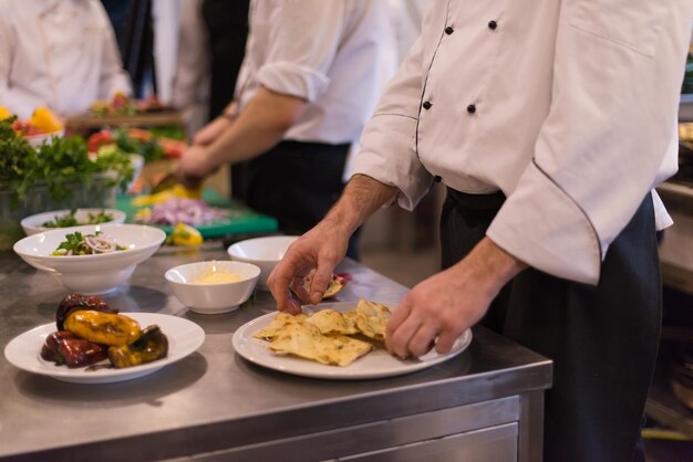 Profesjonalny zespół kucharzy i szefów kuchni przygotowujących posiłek w ruchliwej hotelowej lub restauracyjnej kuchni