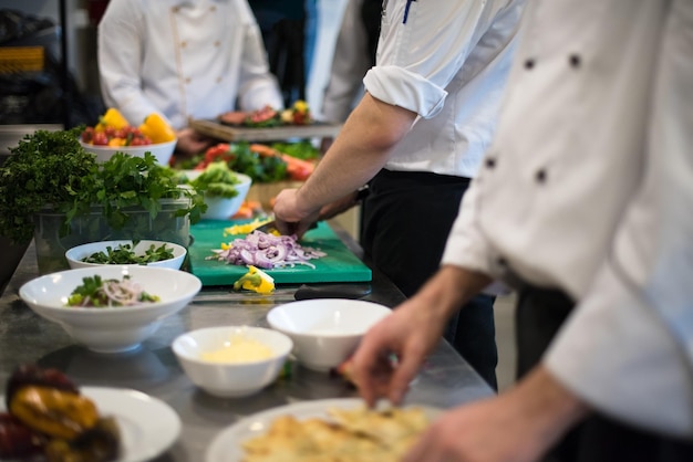 Profesjonalny zespół kucharzy i szefów kuchni przygotowujących posiłek w ruchliwej hotelowej lub restauracyjnej kuchni