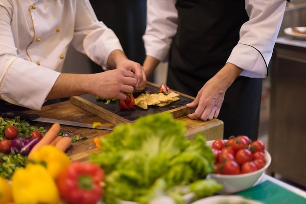 Profesjonalny zespół kucharzy i szefów kuchni przygotowujących posiłek w ruchliwej hotelowej lub restauracyjnej kuchni