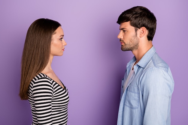 Profil dwóch osób para facet pani stojąca naprzeciwko patrząc oczy mają sytuację konfliktową nosić stylowy strój na co dzień na białym tle pastelowy fioletowy kolor ściany