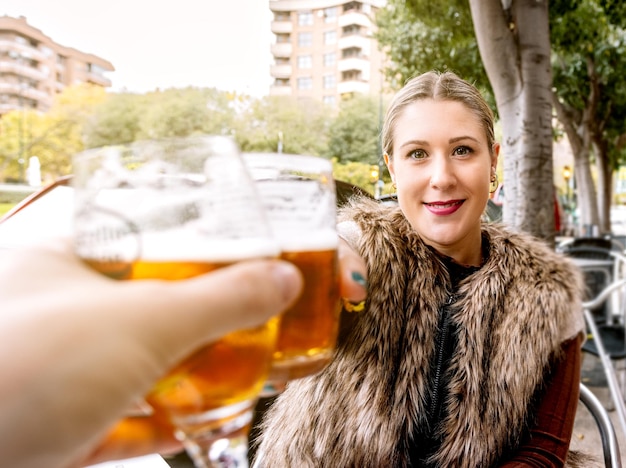 Profil młodej kobiety wznoszącej toast ze szklanką piwa