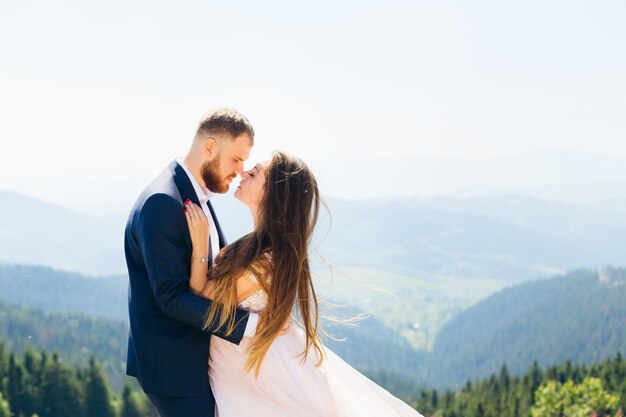 Profil nowożeńców, którzy objęli się i zamknęli oczy na tle górskiej przyrody