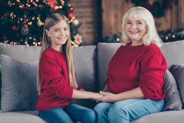 Profilowy portret wnuka babci siedzi na przytulnej sofie, trzymając się za ręce w urządzonym pokoju