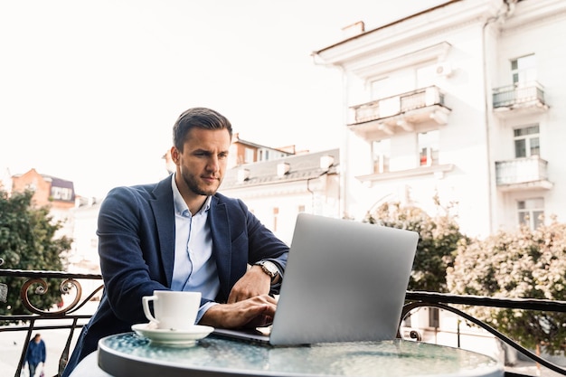 Programista przy filiżance kawy pracuje online za pomocą laptopa w kawiarni. Praca zdalna.