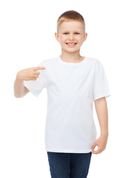 Zdjęcie projekt koszulki i koncepcja reklamy - uśmiechnięty mały chłopiec w pustej białej koszulce wskazujący na siebie