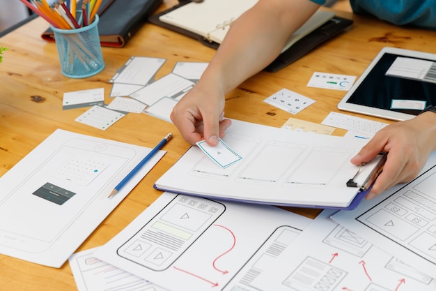 Projektanci graficzni współpracują z projektantem interfejsu użytkownika, planując szablon układu aplikacji dla telefonów komórkowych, komputerów mobilnych