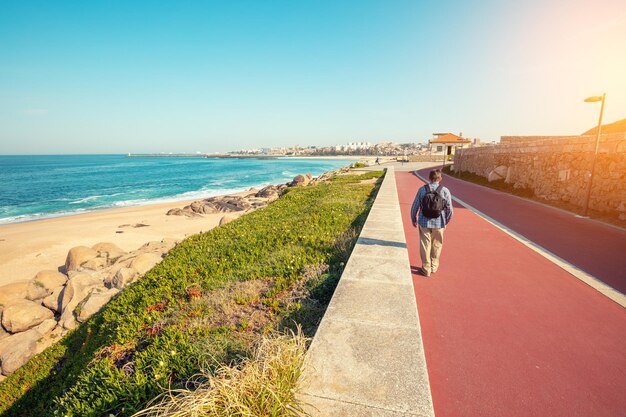 Promenada wzdłuż morza i Oceanu Atlantyckiego wiosną Człowiek spaceruje na nabrzeżu Piękna zatoka w słoneczny dzień Widok na miasto Porto na horyzoncie Portugalia Europa