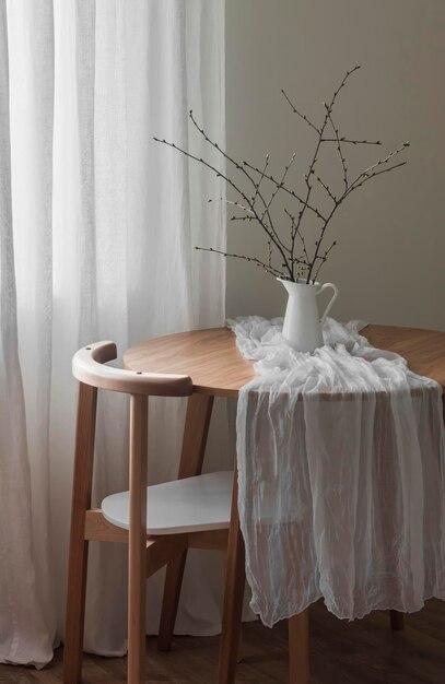 Proste wnętrze salonu okrągły drewniany stół z dzbanem z gałęziami i krzesłem w stylu minimalistycznym