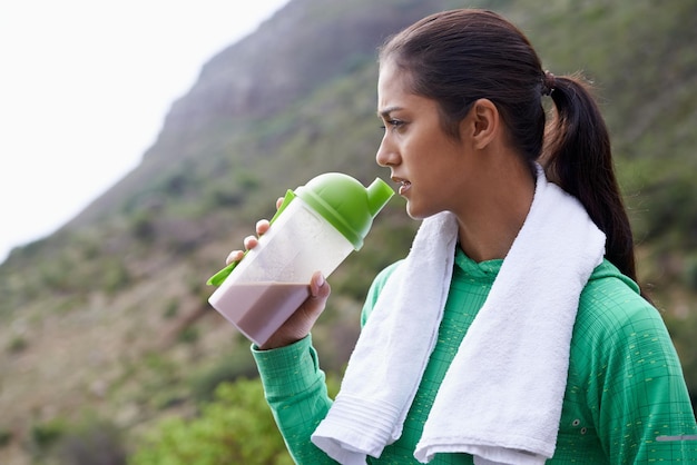 Protein shake drink i ćwiczenia na świeżym powietrzu z butelką dla zdrowia, dobrego samopoczucia i korzyści energetycznych Park przyrody i osoba z smoothie w pojemniku dla odżywiania w diecie po wędrówce lub treningu