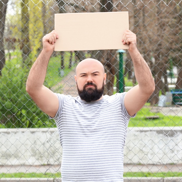 Zdjęcie protestujący młody człowiek trzymający kawałek tektury z miejscem na tekst na ulicy