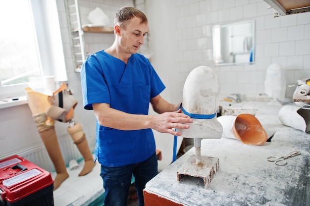 Protetyk człowiek wykonujący protezę nogi podczas pracy w laboratorium, wykonuje model gipsu.