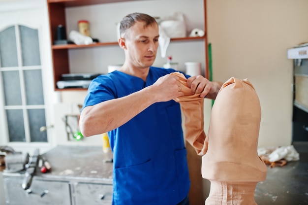 Protetyk mężczyzna wykonujący protezę nogi podczas pracy w laboratorium.