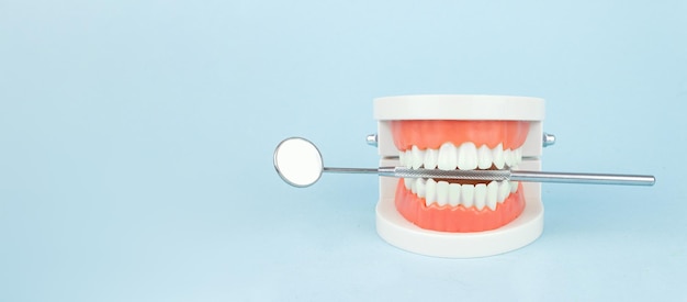 Proteza dentystyczna z lustrem ust dentysty na niebieskim tle zbliżenie Starość Zęby Szczęka