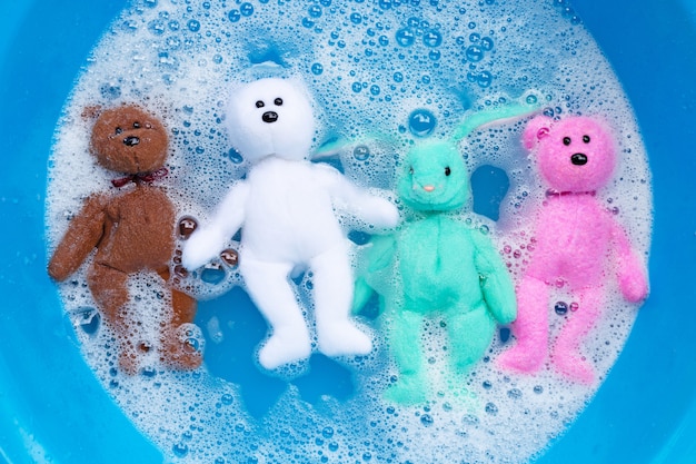 Przed praniem zamocz lalki królika zabawkami z niedźwiedziami w wodzie rozpuszczonej w detergencie do prania. Koncepcja prania,