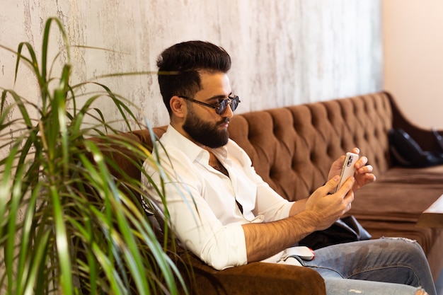 Przedsiębiorca używa telefonu komórkowego młody przystojny biznesmen arabski muzułmanin w centrum biznesowym
