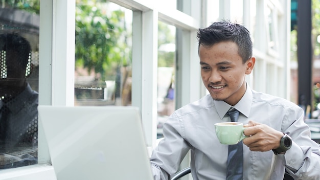 Przedsiębiorcy pracujący przy komputerach, piją kawę i uśmiechają się