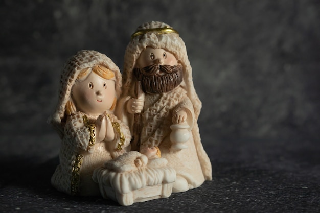 Przedstawienie szopki bożonarodzeniowej z figurkami małego Jezusa, Maryi i Józefa na tle skały.