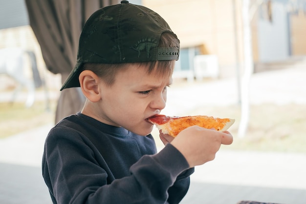 Przedszkolak jedzący pizzę w kawiarni na świeżym powietrzu Pizzeria Styl życia