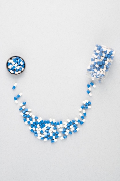 Przegląd małego słoiczka zawierającego niebiesko-białe pigułki tworzące uśmiech zakończony okrągłym wieczkiem