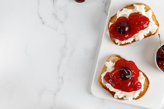 Przekąska tostowa bruschetta Przystawka z dżemem serowym ricotta i wiśniami na białej tablicy