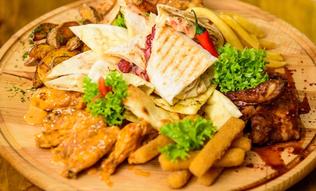 Przekąska z menu pubu Mięsna przekąska dla grupy przyjaciół Smaczne, pyszne przekąski Jedzenie w restauracji Przekąska do piwa Drewniana deska frytki Paluszki rybne Burrito i stek mięsny podawany z sałatką Smacznego posiłku