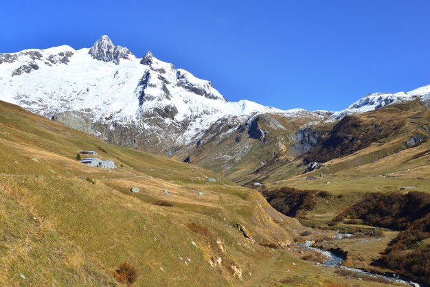 przekraczanie rzeki alpejska dolina ze śnieżnym szczytem górskim tłem pod błękitnym niebem