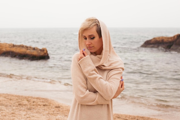 Przemyślana kobieta nosi sukienkę w pobliżu morza jesienią