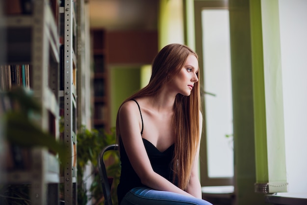 Przemyślana koncepcja. siedząca biblioteka kobiety dziewczyna