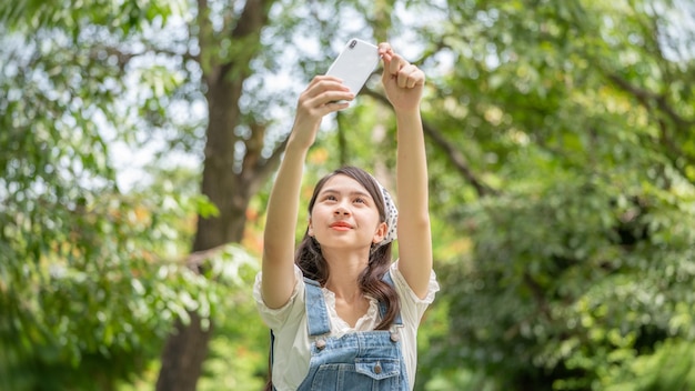 Przemyślana Uśmiechnięta Kobieta W Parku Używająca Smartfona Do Robienia Zdjęć Selfie Portret Młodego Czarującego