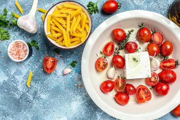 Przepis na makaron zapiekany feta z pomidorkami koktajlowymi, serem feta, czosnkiem i ziołami w naczyniu żaroodpornym.