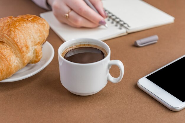 Przerwa na kawę z rogalikiem i espresso. Kobieta pisze na notebooku. Freelancer w pracy