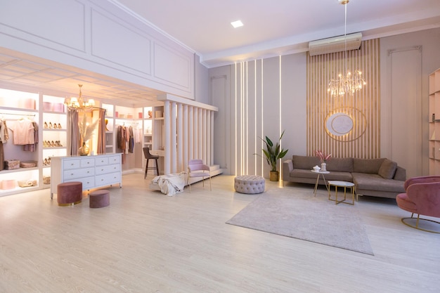 Przestronne drogie luksusowe jasne wnętrze otwartego apartamentu w różowych kolorach z garderobą, częścią sypialną i przytulną strefą dla gości z miękkimi meblami. modne oświetlenie LED i ogromne okna
