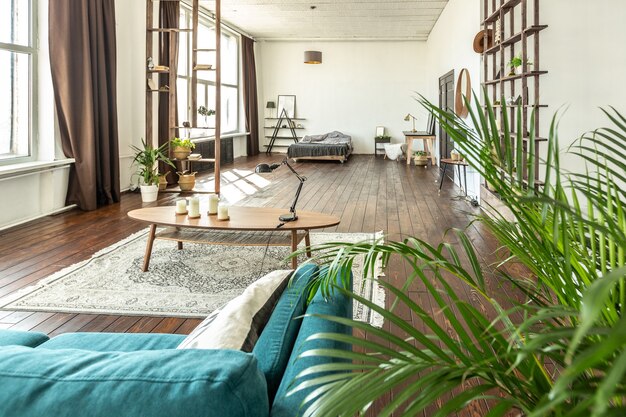 Zdjęcie przestronny apartament typu studio urządzony w drewnie i bieli. minimalistyczny design z ogromnymi oknami w słońcu. kuchnia i salon