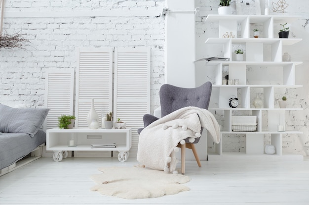 Zdjęcie przestronny stylowy nowoczesny modny loft w biało-szarych barwach pełnych słońca. ceglana ściana, regały, łóżko z palet i domek dla dzieci w kształcie tipi.