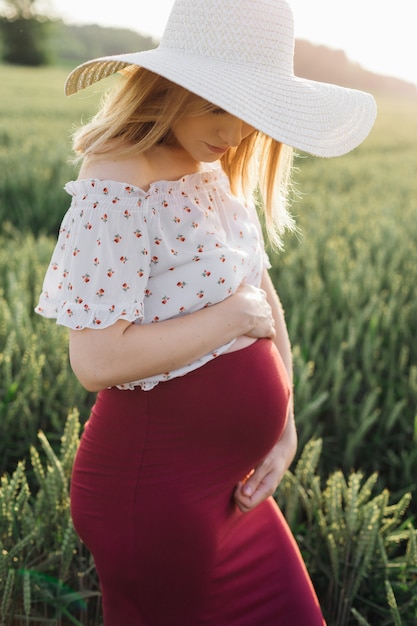 Przetarg i wzruszający portret młodej kobiety w ciąży. Biała czapka podkreśla kobiecość i piękno. Opieka nad ciążą. Piękno i zdrowie. Szczęście i spokój. Styl życia. Produkty dla kobiet w ciąży.