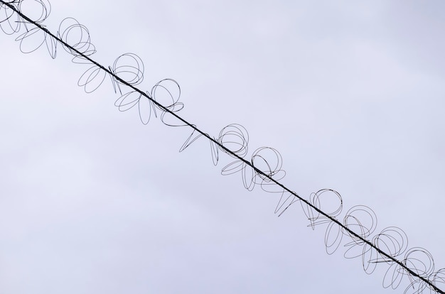 Przewody wysokiego napięcia ze spiralną cewką na tle błękitnego nieba Drut skręcony z białym bondage Przemysł elektryczny