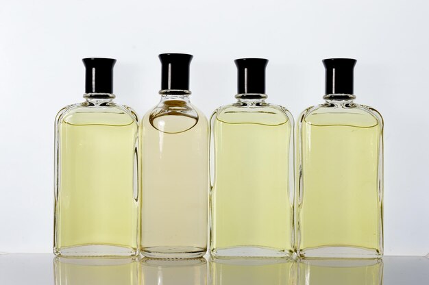 Przezroczyste szklane słoiki z płynem perfumowym stoją na białej powierzchni