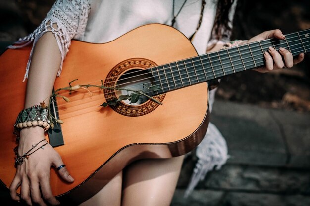 Zdjęcie przycięta postać hippie z boho drewnianymi bransoletkami z perłami trzymającą gitarę