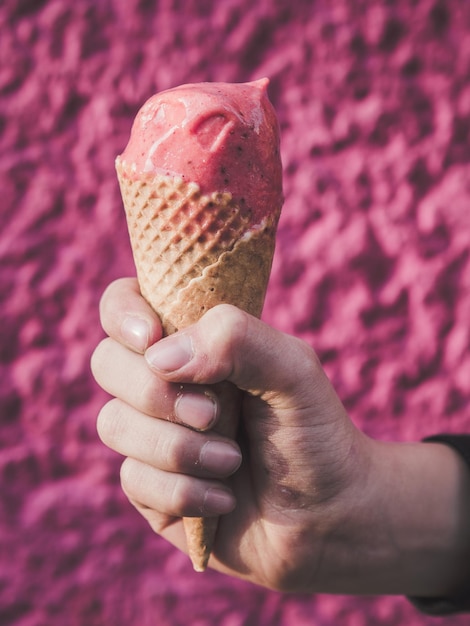 Przycięta ręka chłopca trzymającego lody na ścianie