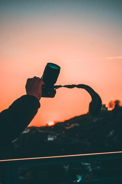 Przycięta Ręka Człowieka Fotografującego Kamerą Na Pomarańczowym Niebie