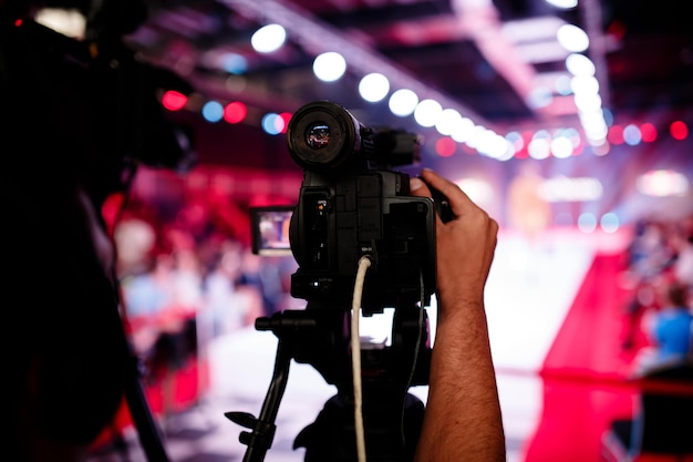 Przycięta ręka fotografa dostosowującego kamerę telewizyjną na statywie podczas pokazu mody