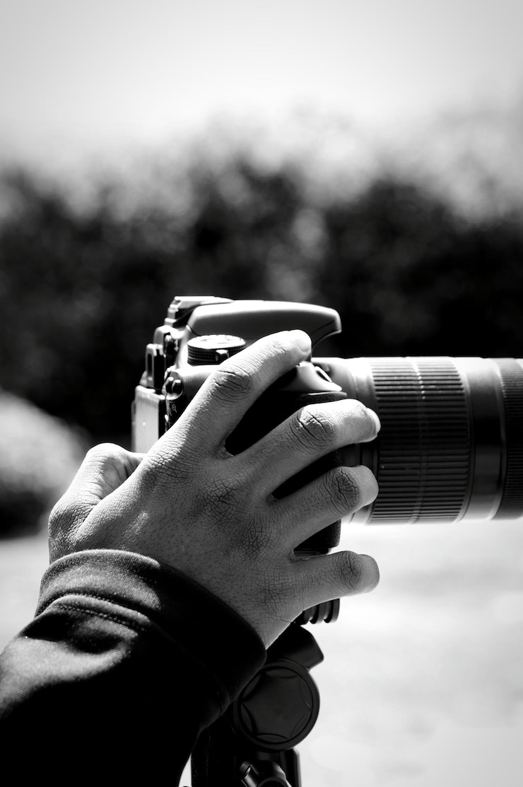 Zdjęcie przycięta ręka fotografuje kamerą na tle nieba w słoneczny dzień