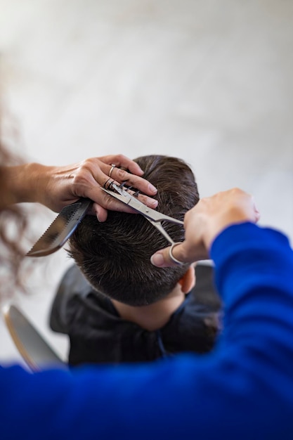 Przycięta ręka fryzjera przycinającego włosy w salonie